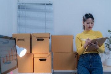 Focused young asian entrepreneur checking inventory in office at night, managing logistics for...