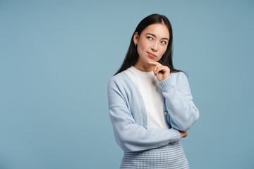 Pensive, attractive, Asian woman looking away and touching her chin in contemplation looking away