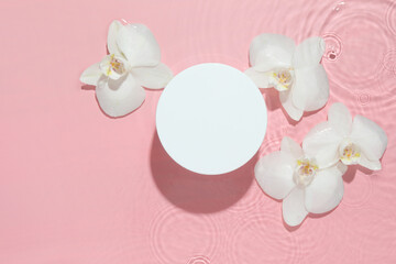 Beautiful orchid flowers and podium in water on pink background, flat lay. Presentation for product