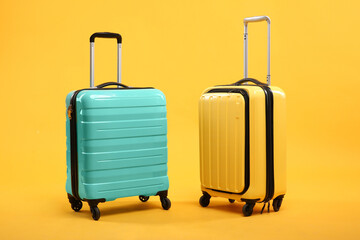 Two different bright suitcases on yellow background