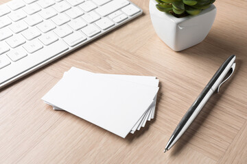 Blank business cards, pen and keyboard on wooden table. Mockup for design