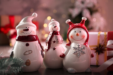 Funny snowmen figures and Christmas decor on table, closeup