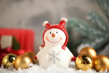Funny snowman figure and Christmas decor on artificial snow, closeup
