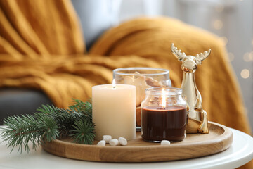 Burning candles, fir branches and decorative deer on coffee table indoors. Christmas atmosphere