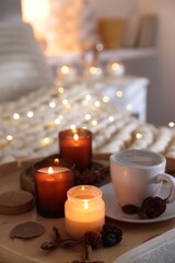 Burning candles, lights, coffee and decor on bed indoors. Autumn atmosphere