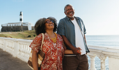 Mature couple holding hands and enjoying a relaxed walk at Farol da Barra, Bahia