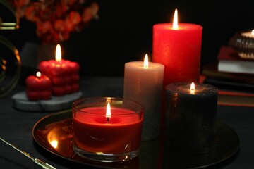 Beautiful burning candles and decor on black table, closeup