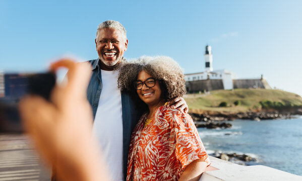 Happy retired couple enjoying a holiday on the coast at Farol da Barra, Bahia