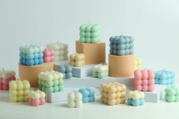 Many beautiful bubble candles and podiums on white table