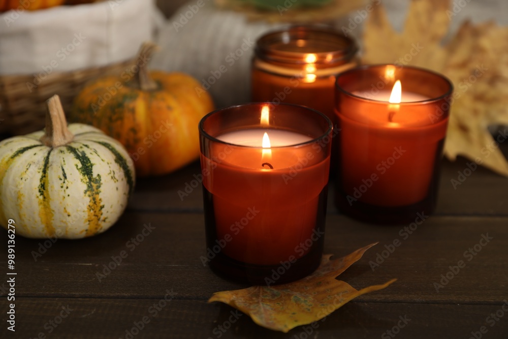 Sticker Burning candles and autumn decor on wooden table, closeup