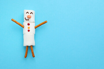 Funny snowman made of marshmallows on light blue background, top view. Space for text