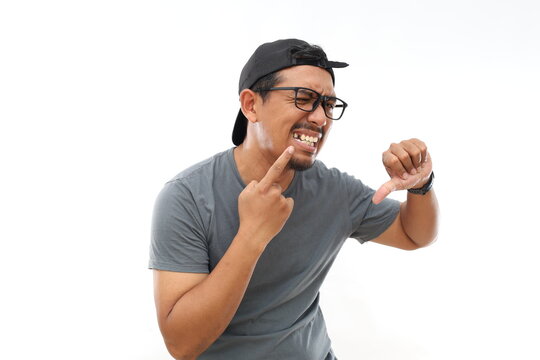 Unhappy Asian man pointing his missing teeth while showing thumbs down. Isolated on white