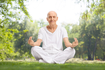 Fototapeta premium Elderly man in white clothes meditating