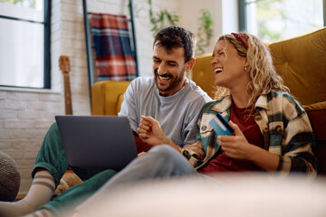 Cheerful couple shopping online while relaxing at home.