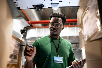 Naklejka premium Professional courier loading his delivery truck with packages and parcels. Ready to deliver.