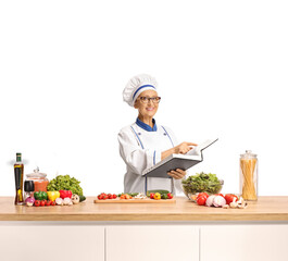Female chef reading a recipe in a cook book and preparing a meal