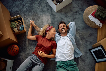 Above view of happy couple relaxing on carpet after moving into new house.