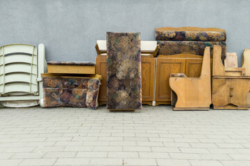 Old upholstered furniture and wooden items stacked outdoors