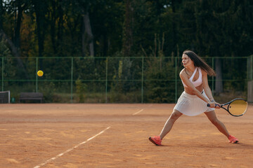 Young woman playing tennis outdoor at summer