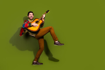 Fototapeta premium Photo of cheerful crazy man wear stylish clothes play guitar instrument isolated on khaki color background