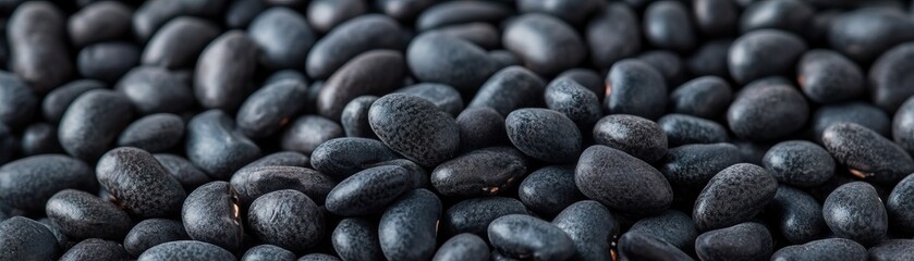Close-up of black beans scattered on a surface, showcasing their shiny texture and rich color, ideal for culinary themes.