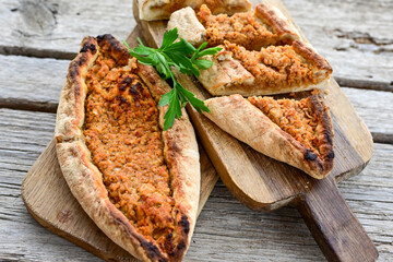  Traditional Turkish cuisine. Baked Pide dish with chicken ,  cheese and  herbs on  wooden background.  Turkish pizza pide