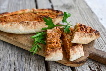  Traditional Turkish cuisine. Baked Pide dish with chicken ,  cheese and  herbs on  wooden background.  Turkish pizza pide