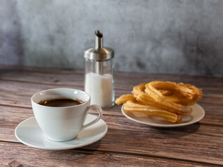 Hot chocolate breakfast in white cup with churros on wooden table