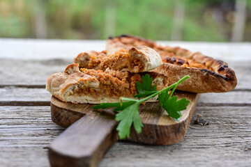  Traditional Turkish cuisine. Baked Pide dish with chicken ,  cheese and  herbs on  wooden background.  Turkish pizza pide