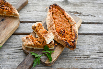  Traditional Turkish cuisine. Baked Pide dish with chicken ,  cheese and  herbs on  wooden background.  Turkish pizza pide