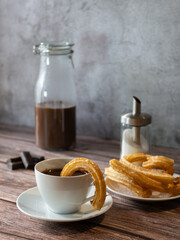 Vertical photo of a hot chocolate with churros. Churro inside the chocolate cup