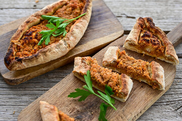  Traditional Turkish cuisine. Baked Pide dish with chicken ,  cheese and  herbs on  wooden background.  Turkish pizza pide