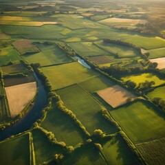 A tranquil aerial drone image of vast, green farmlands stretching across the countryside. Neatly divided plots of land create geometric patterns, while a river snakes its way through the fields