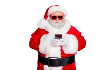 Portrait of minded santa claus with eyewear eyeglasses using cell phone device reading news wearing costume isolated over red background