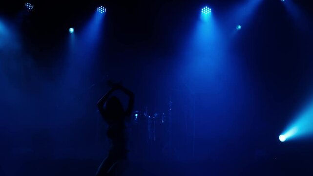 Asian women dancing sexy dance moves and body shapes on stage with blue lights at night.