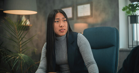 Obraz premium Angry and aggressive Asian woman loses temper, starts fight, shouts at boyfriend or husband during couples therapy session. Couple or young family having conflict on consultation with psychotherapist.