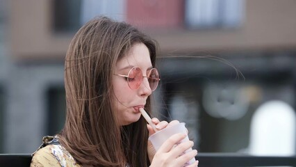 Pensive happy woman sipping a milkshake in the street