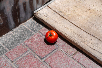 Eine Tomate, die auf dem Steinboden aus komischen Fliesen liegt 