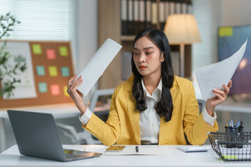 Young businesswoman is feeling confused and stressed while working with documents at her desk in a...