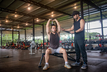 A personal trainer is showing trainee the correct way to perform exercises in the fitness center