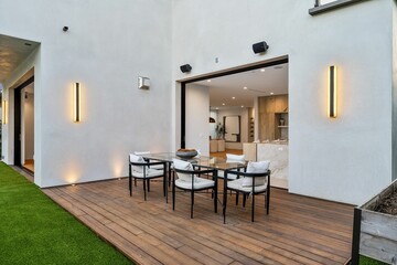 Modern outdoor dining area with a wooden deck and glass table.