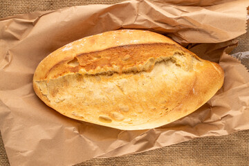 One white bread on a paper bag, macro, top view.