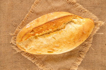 One white bread on a jute cloth, macro, top view.
