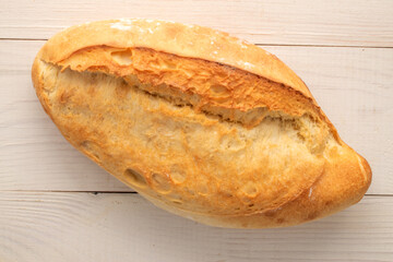 One white bread on a wooden table, macro, top view.