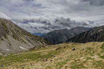 Picturesque landscape on the peak of the mountain with snow and green grass at summer, cloudy in the mountains of Andorra, Arinsal