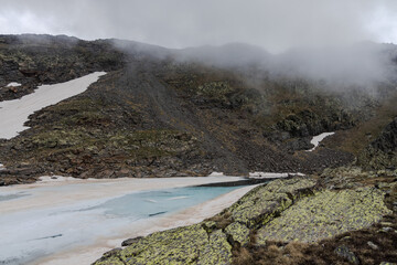 Bright blue glasier in cloudy mountains, frozen lake Montmantell in the summer in Andorra