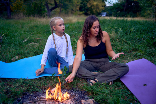 mother and her daughters  roasting and eating marshmallows on the campfire, camping vacation with children, mosquito bites on children's faces