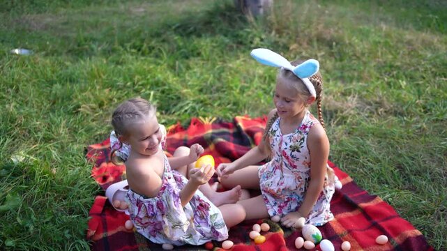 little girls, sisters, playing on a picnic blanket with eggs after  Easter egg hunt