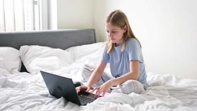 Cute Preschool Girl Surfing The Internet Early In The Morning On The Weekend While In Bed