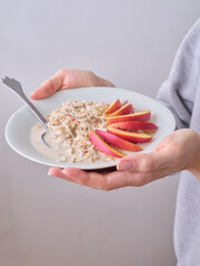 Overnight oats with nectarine and peach topping. A breakfast bowl in female hands